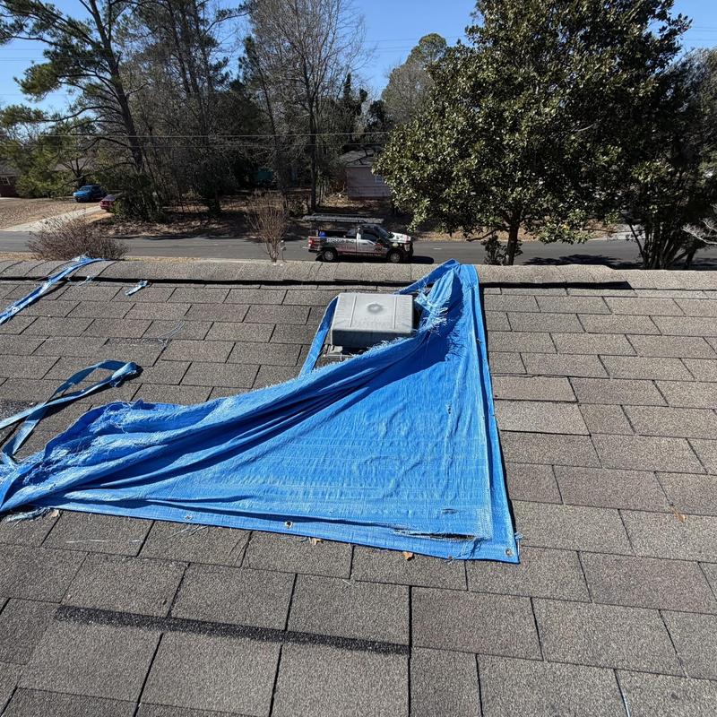 Roof vent with protective blue tarp on shingled roof