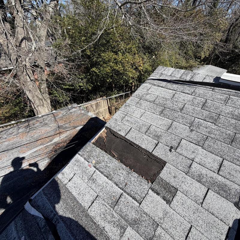 Roof shingles with damaged, missing section on house roof