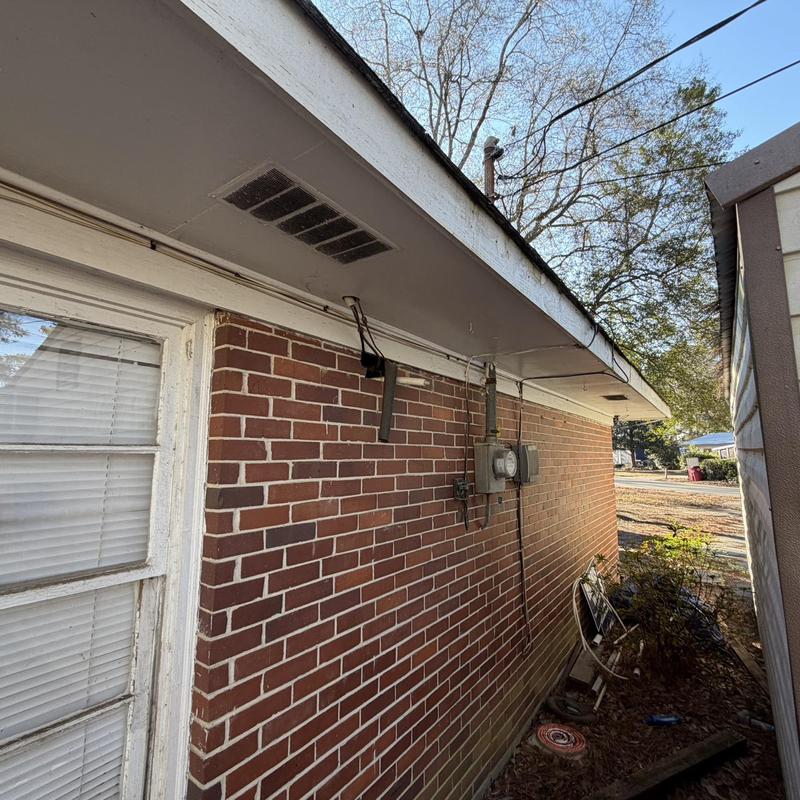 Wood soffit with rot under roof edge on brick house