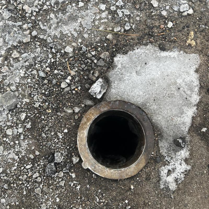 Main sewer line cleanout with missing cap in pavement