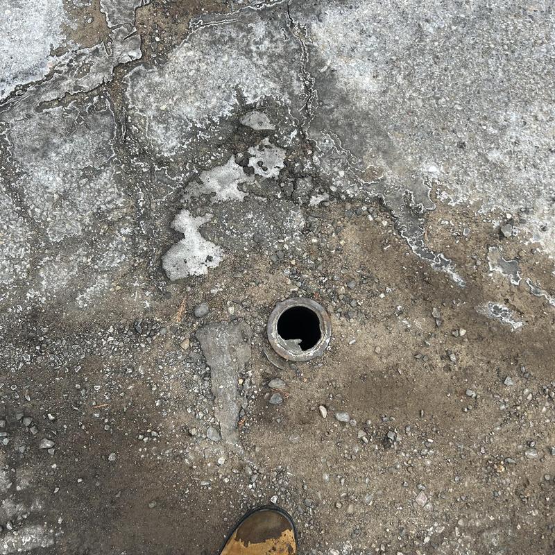 Sewer cleanout pipe opening in frozen ground outdoors