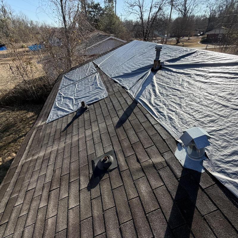 Asphalt shingle roof with tarp covering damaged areas