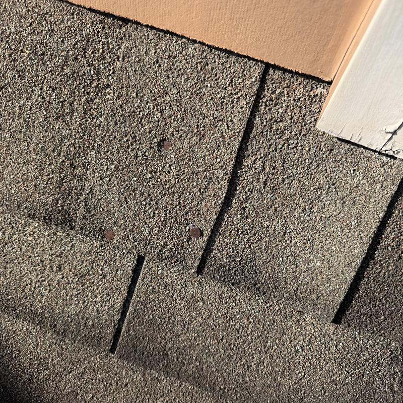 Roof shingles with missing sealant on nails near trim