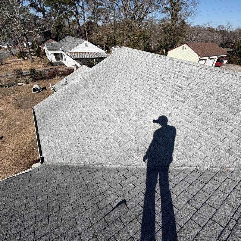 Asphalt shingle roof inspection with shadow of worker