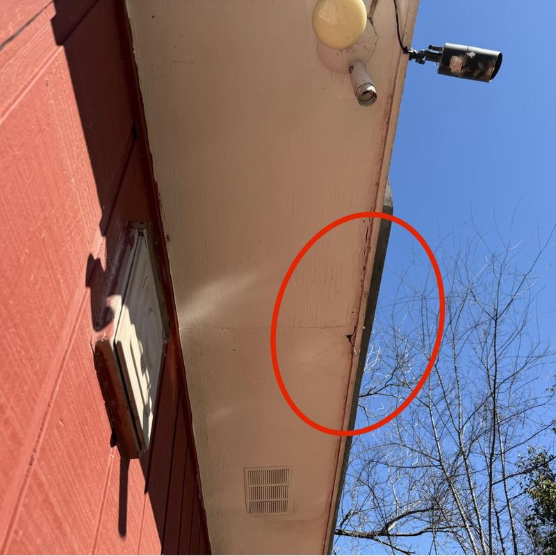 Soffit damage with crack circled under eaves