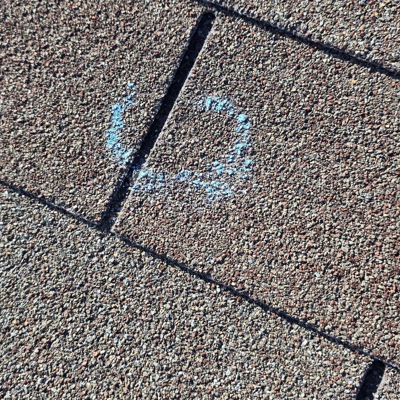 Roof shingles with hail damage marked in blue chalk