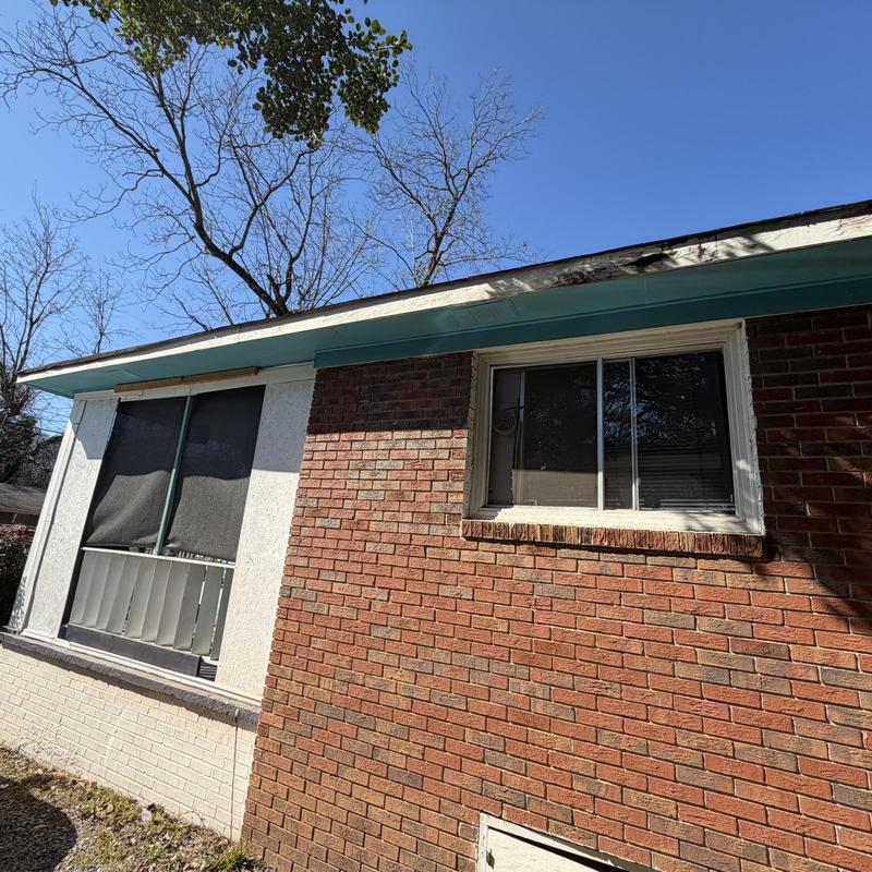 Fascia and soffit damage on brick house exterior under roofline
