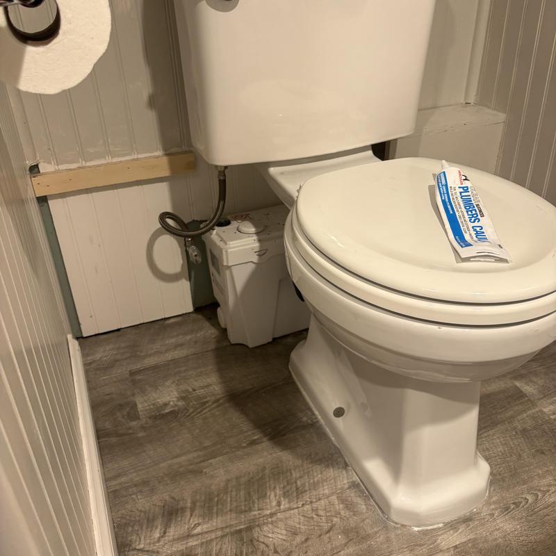 Sewage ejector toilet with pump and plumbing sealant tube