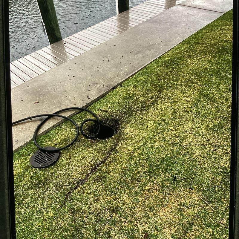 Residential drain with hydro jetting hose on grass near water