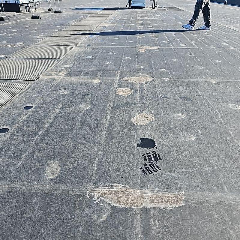 Flat roof with multiple worn and damaged patches Flat roof with multiple worn and damaged patches