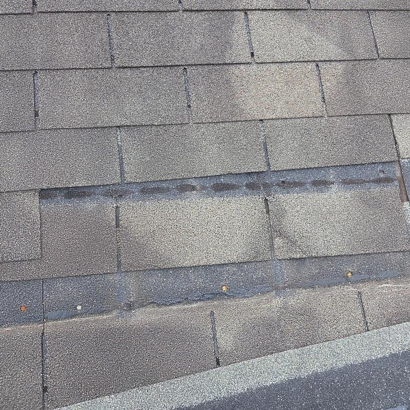Asphalt roof shingles with exposed nail heads and missing shingle section