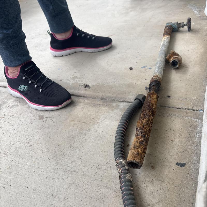Rusty water main pipe and valve removed on concrete floor