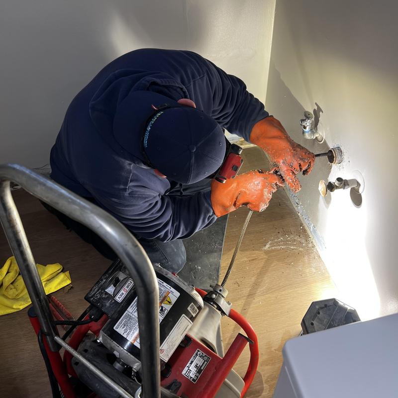 Sink drain plumbing snake clearing under countertop