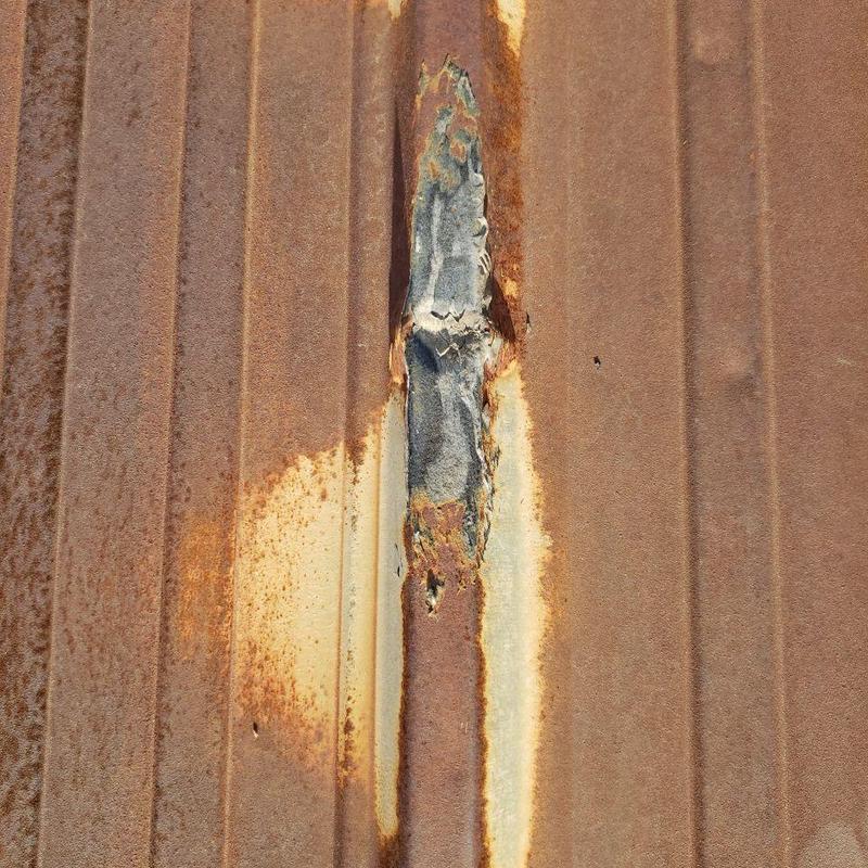 Metal pro-panel roof with surface rust and perforation Metal pro-panel roof with surface rust and perforation