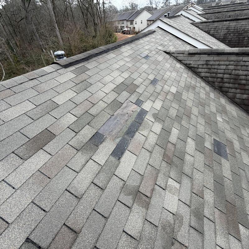 Missing roof shingles with temporary wooden patch