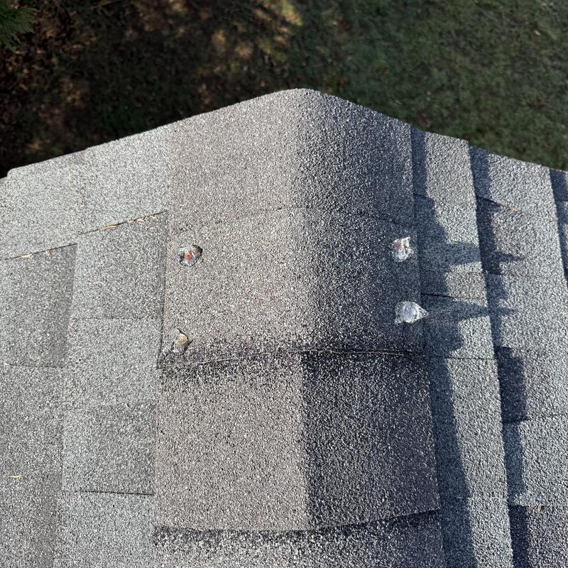 Roof ridge cap with sealed exposed nails on charcoal shingles