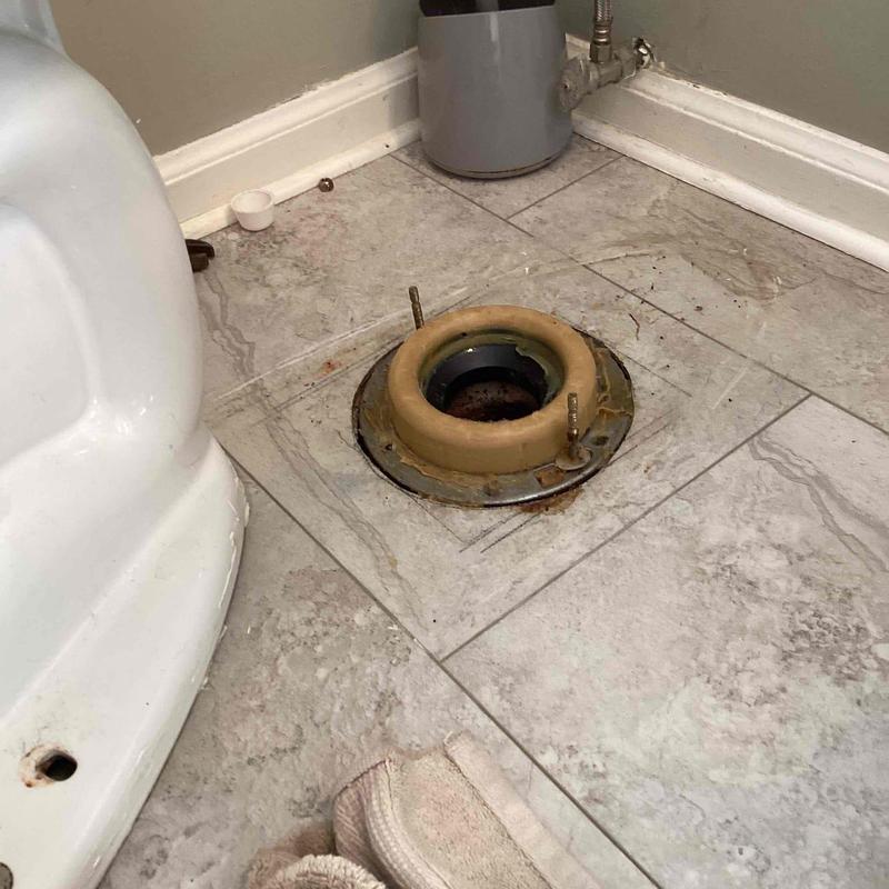 Toilet flange on tiled bathroom floor with removed toilet