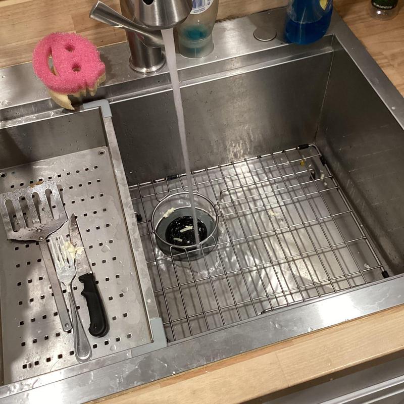 Kitchen sink drain with running water and utensils