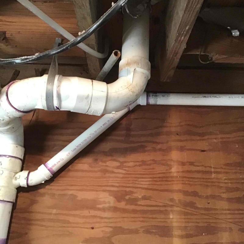 PVC plumbing drain pipes under wooden floor joists