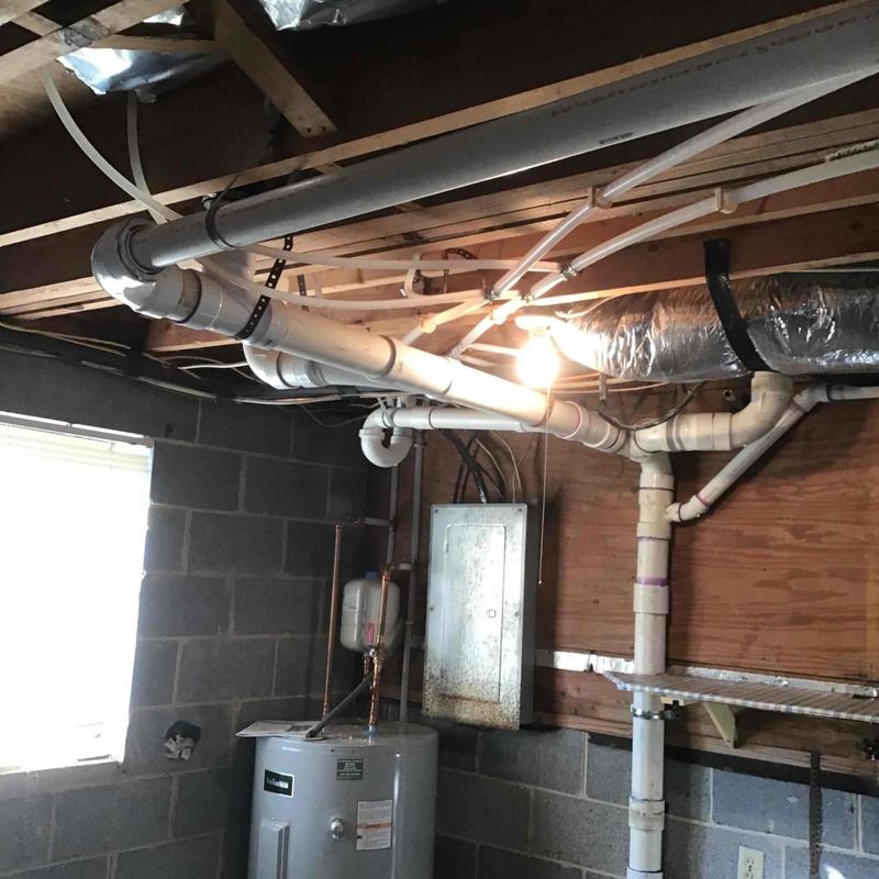 PVC plumbing pipes and water heater in basement