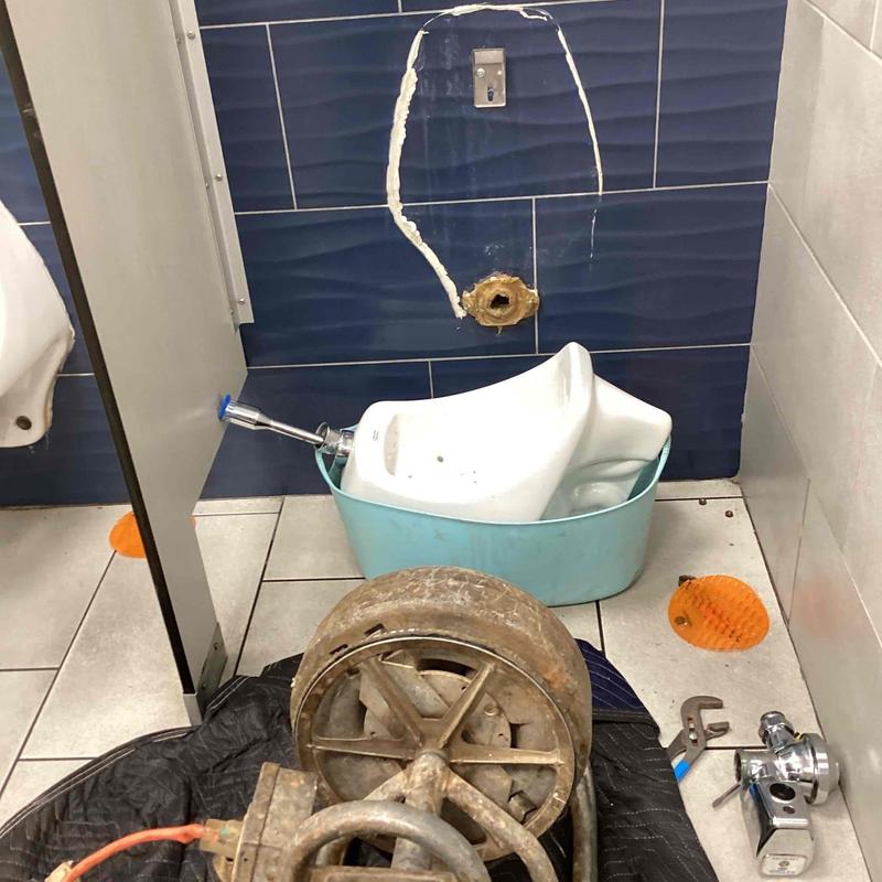 Urinal drain line with removed fixture and plumbing tools