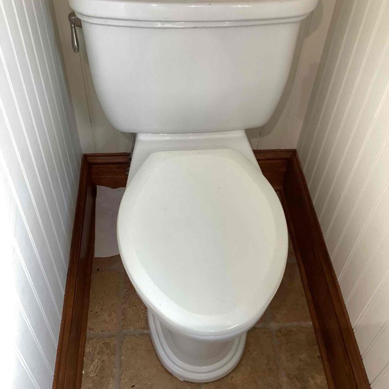 Toilet bowl and tank in small bathroom corner