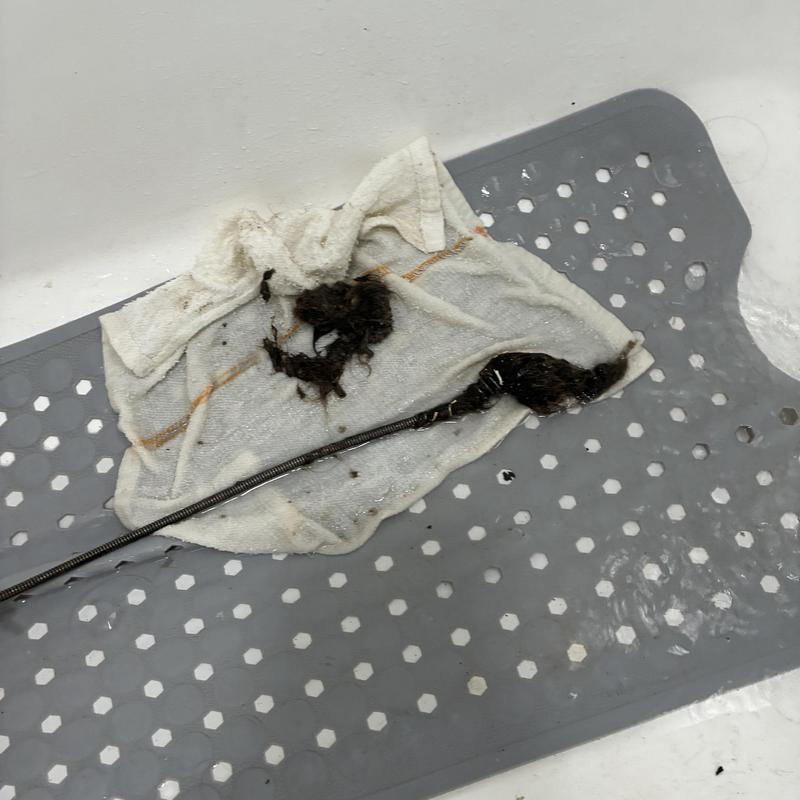 Bathtub drain clog removal with hair blockage on towel