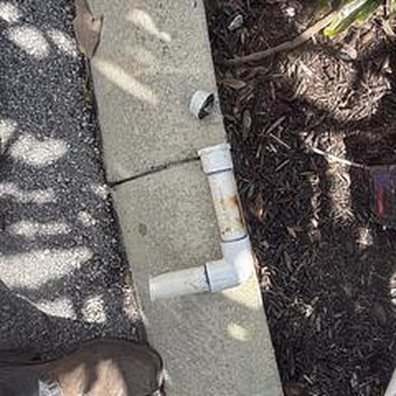 Backflow assembly with PVC pipe repair on sidewalk edge