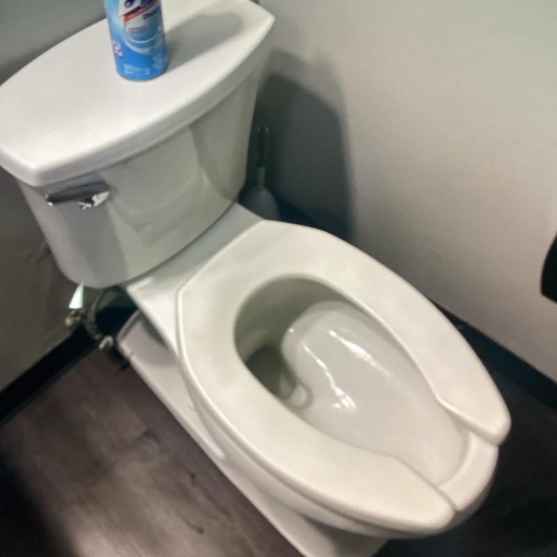 Toilet with open front seat in bathroom corner