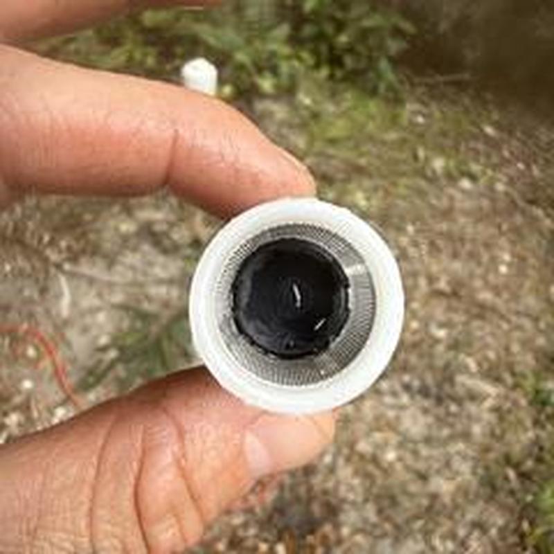 Water heater inlet filter being cleaned by hand