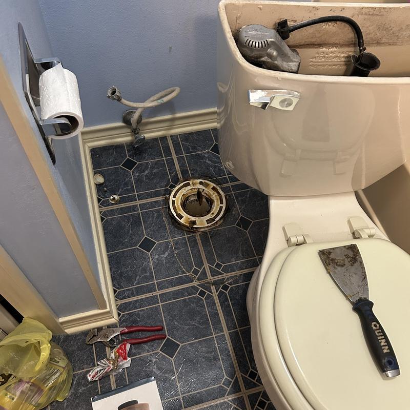 Toilet flange and tank work with tools on tiled floor