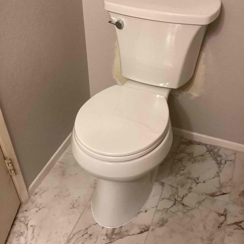 Toilet installation with marble tile flooring and beige walls