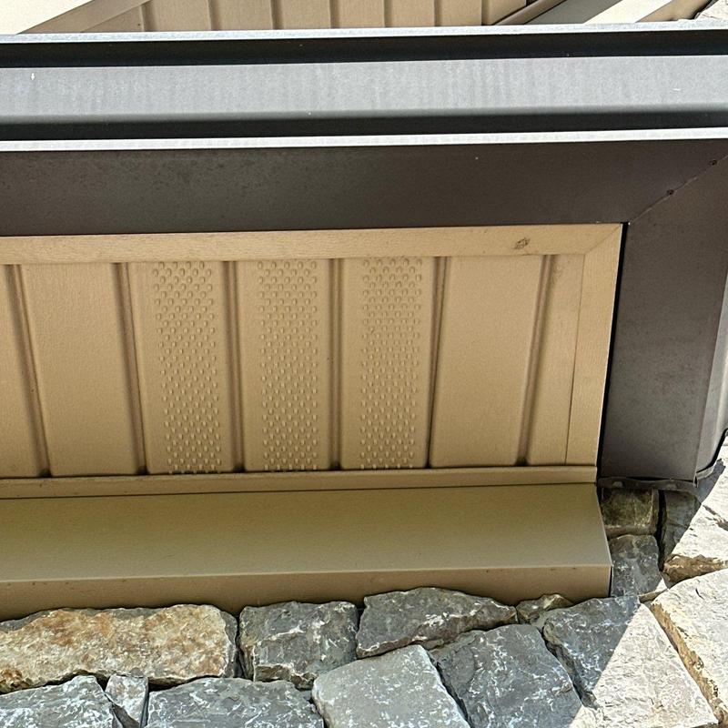 Metal house siding and stone foundation joint close-up