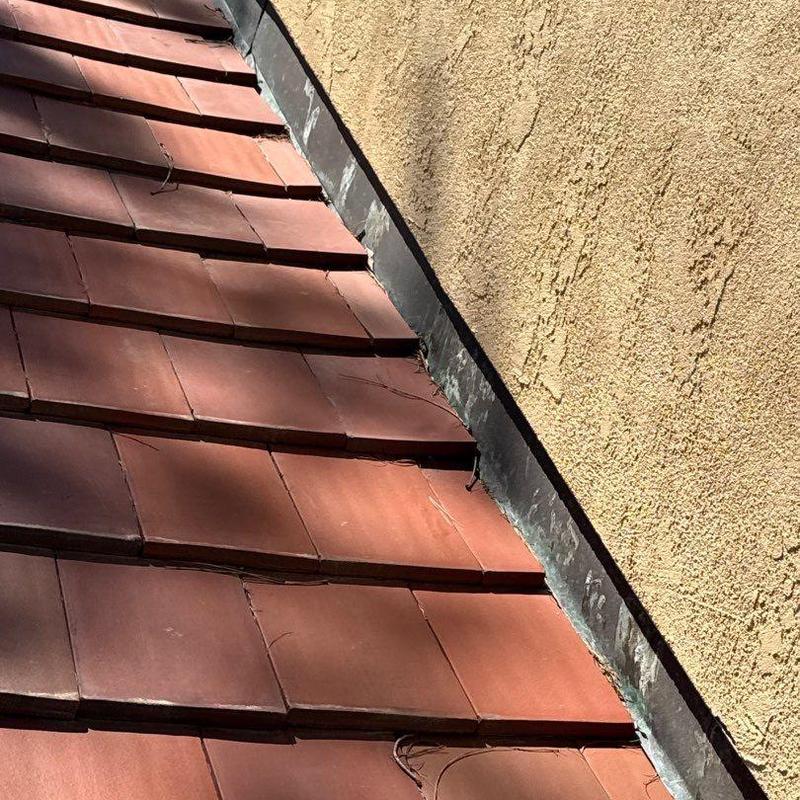 Clay tile roof with metal flashing by stucco wall