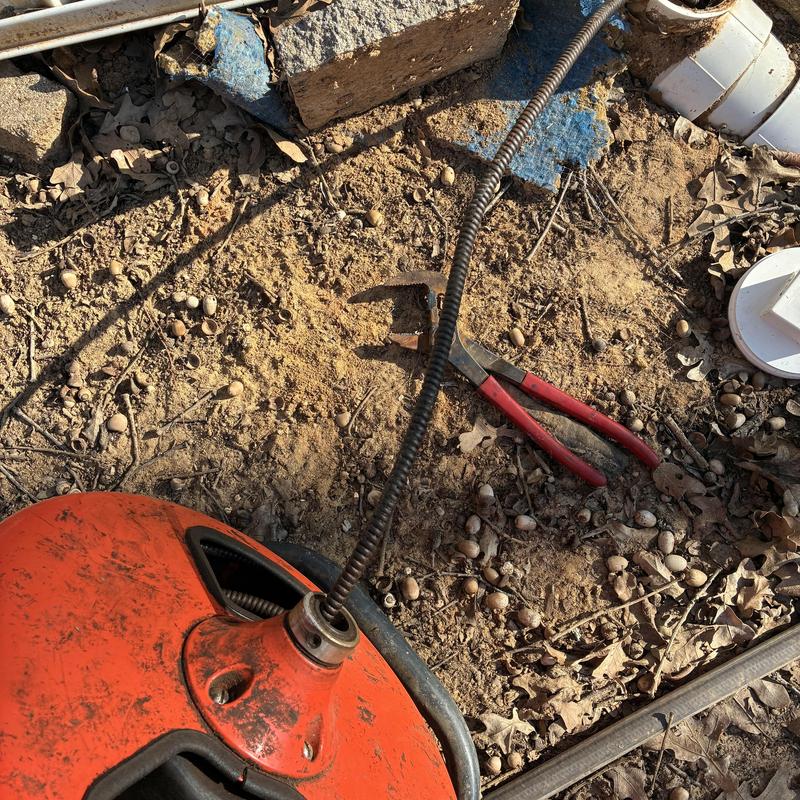 Sewer cleaning machine with clog clearing tool outdoors