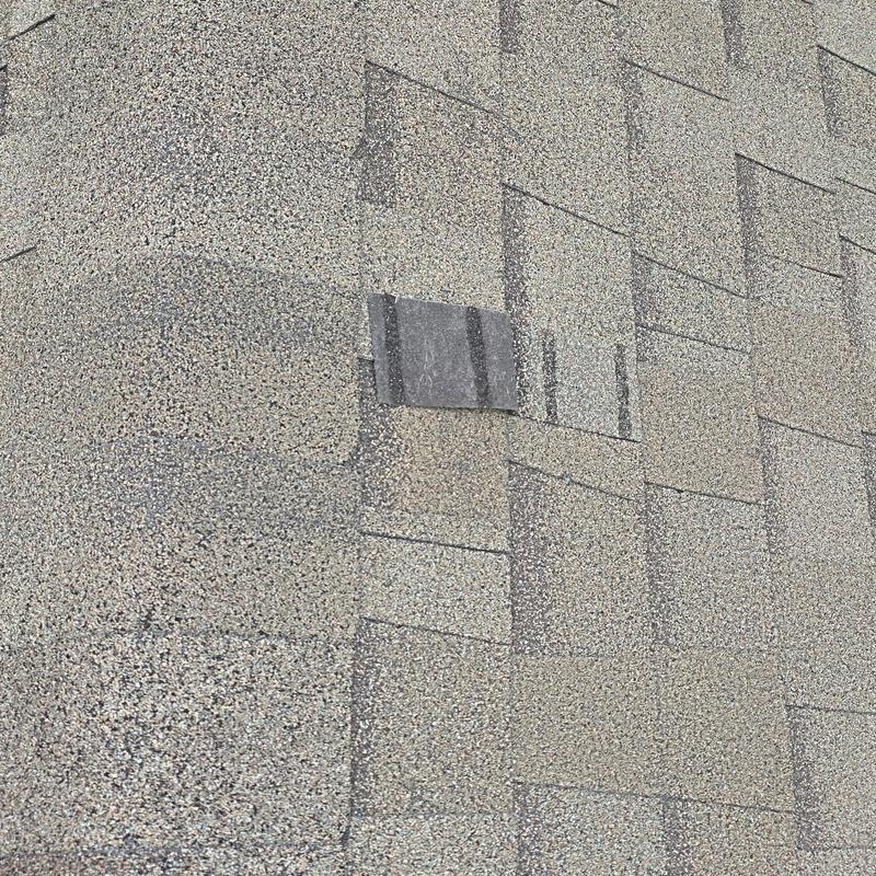 Roof shingles with hail damage and repairs visible