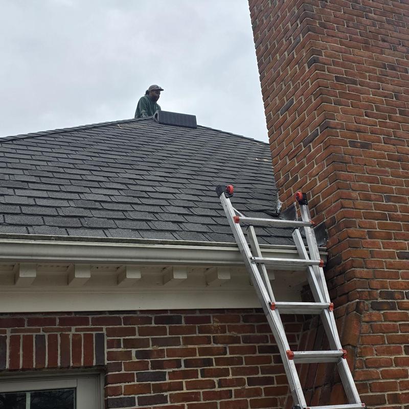 Asphalt shingle roof with chimney and ladder on slope