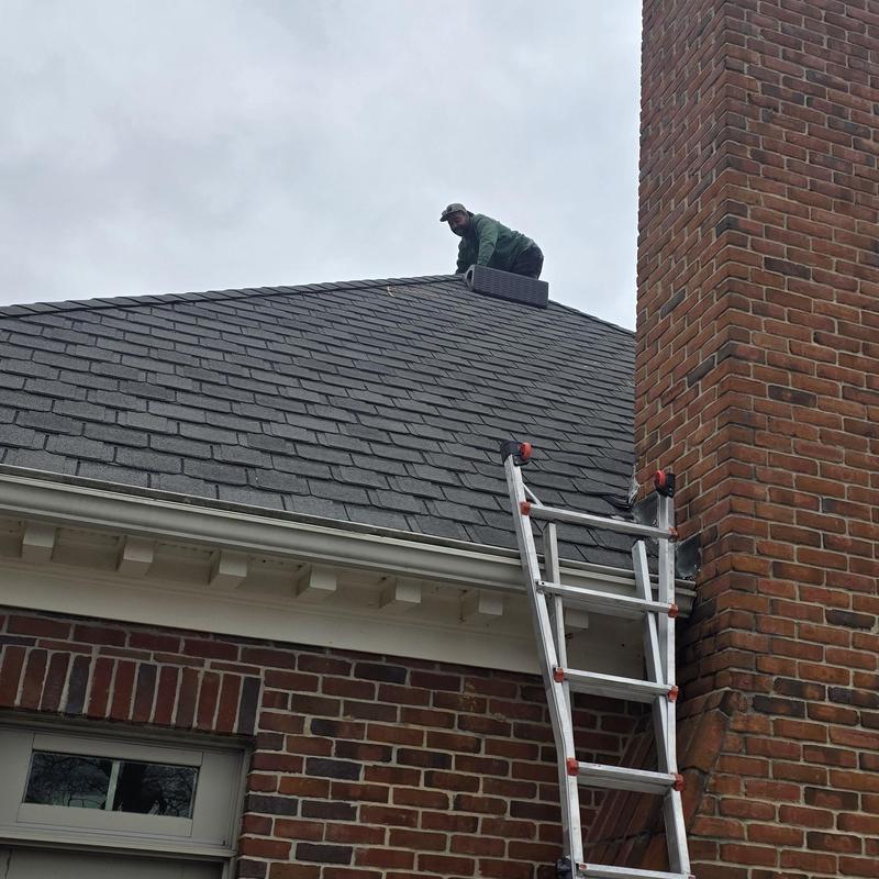 Asphalt shingle roof inspection with ladder near chimney