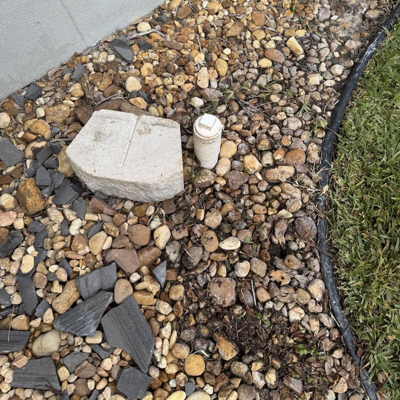 Outdoor cleanout pipe surrounded by gravel and grass