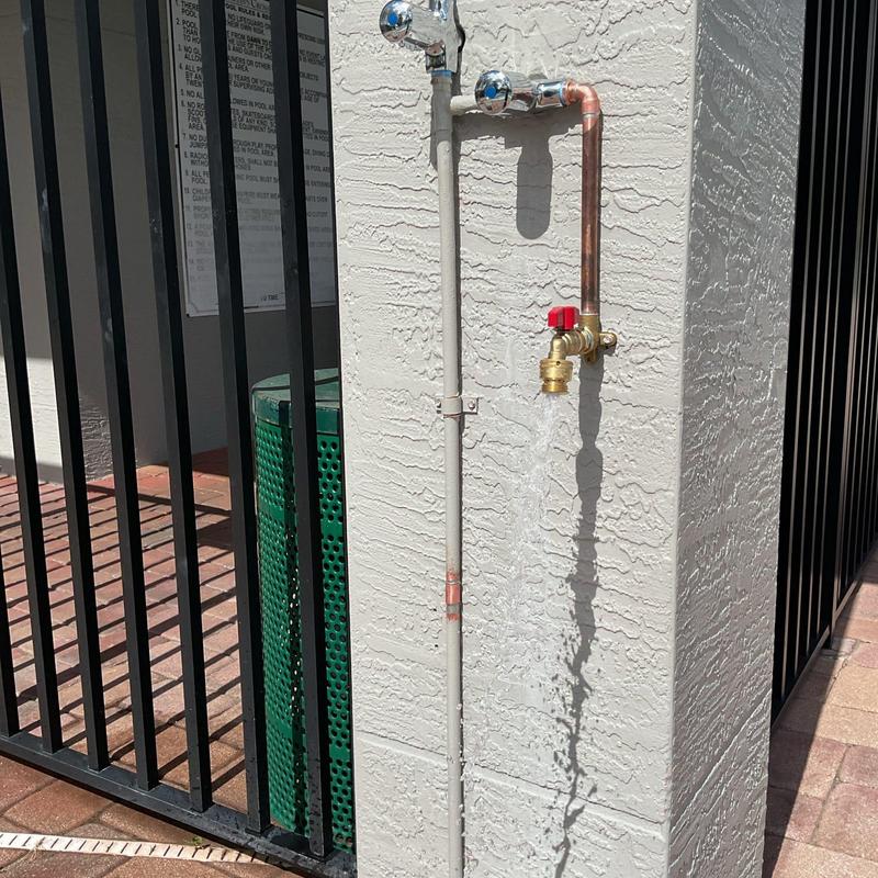 Hose bib with running water on stucco wall