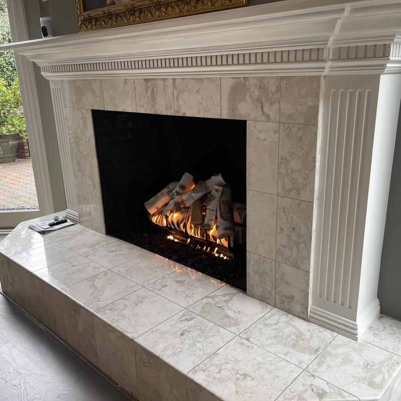 Gas log lighter installation in fireplace with flame