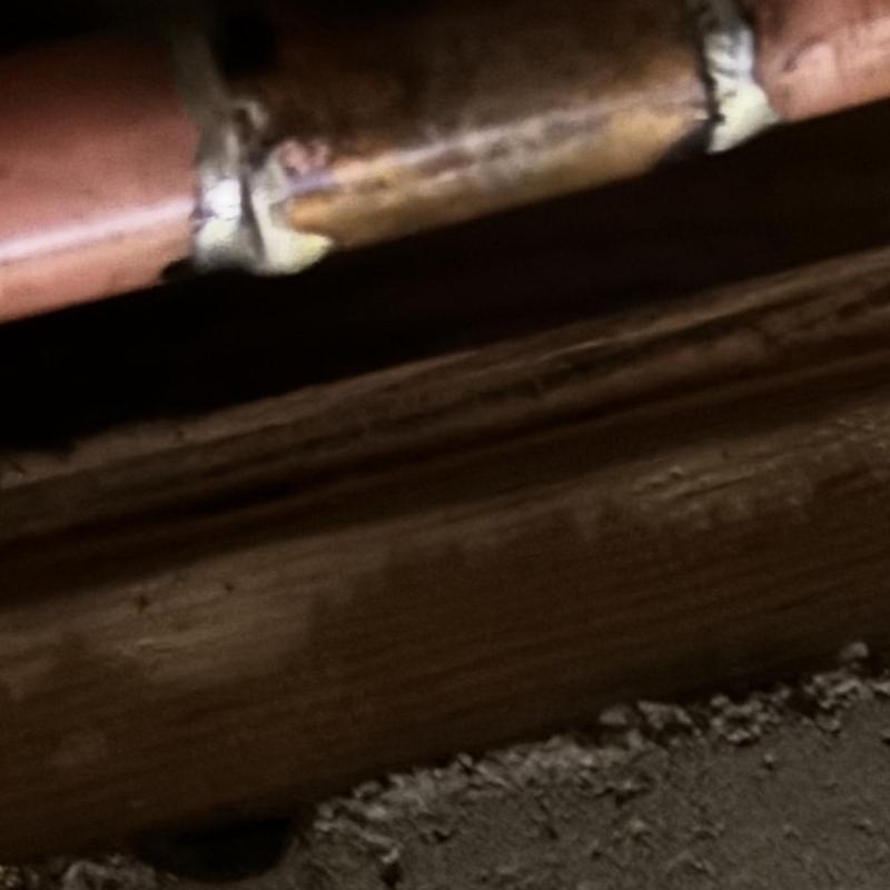 Copper water pipe with leak repair under home