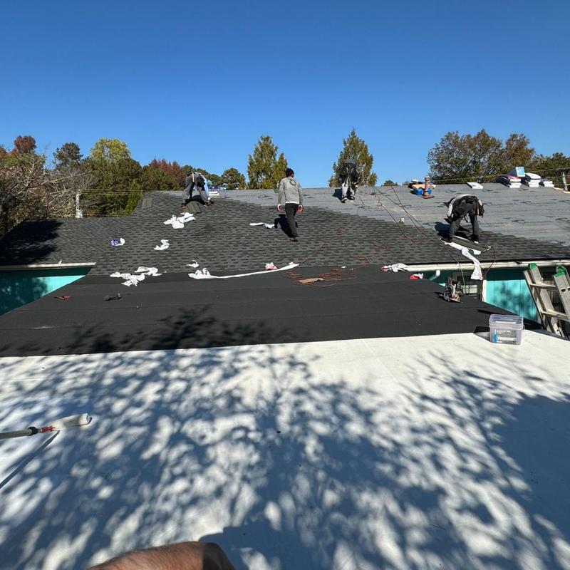 Asphalt shingle roof installation with workers on slope Asphalt shingle roof installation with workers on slope