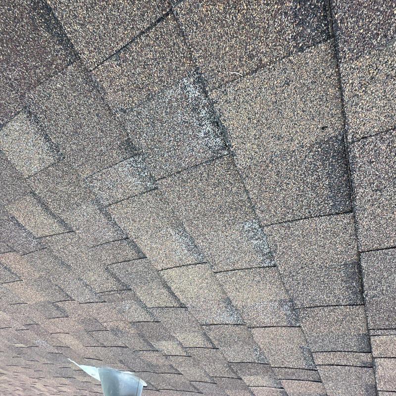 Hail-damaged asphalt roof shingles close-up view