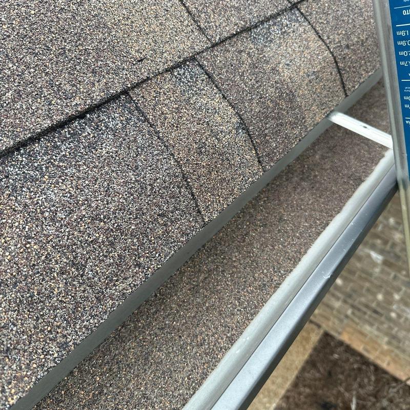 Asphalt shingle roof with hail damage near gutter edge