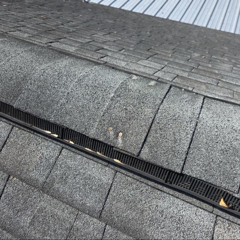 Asphalt shingle ridge vent with hail impact marks