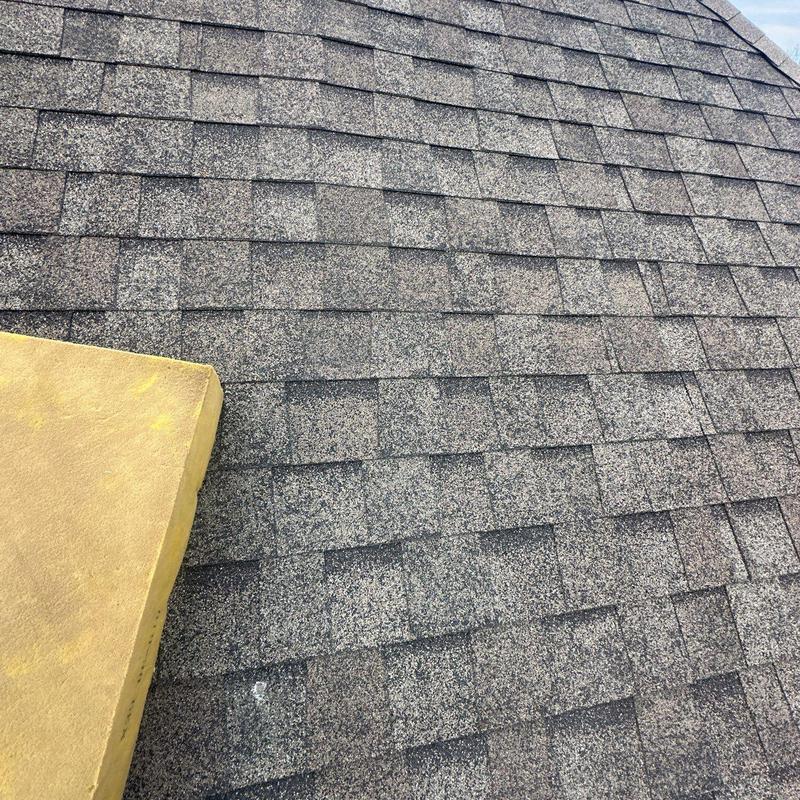 Asphalt roof shingles with hail impact damage near chimney
