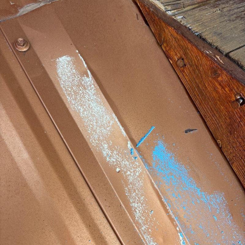 Metal roof panel with hail damage and paint marks