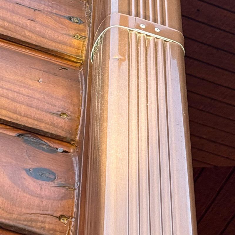 Gutter downspout joint with metal strap fastener