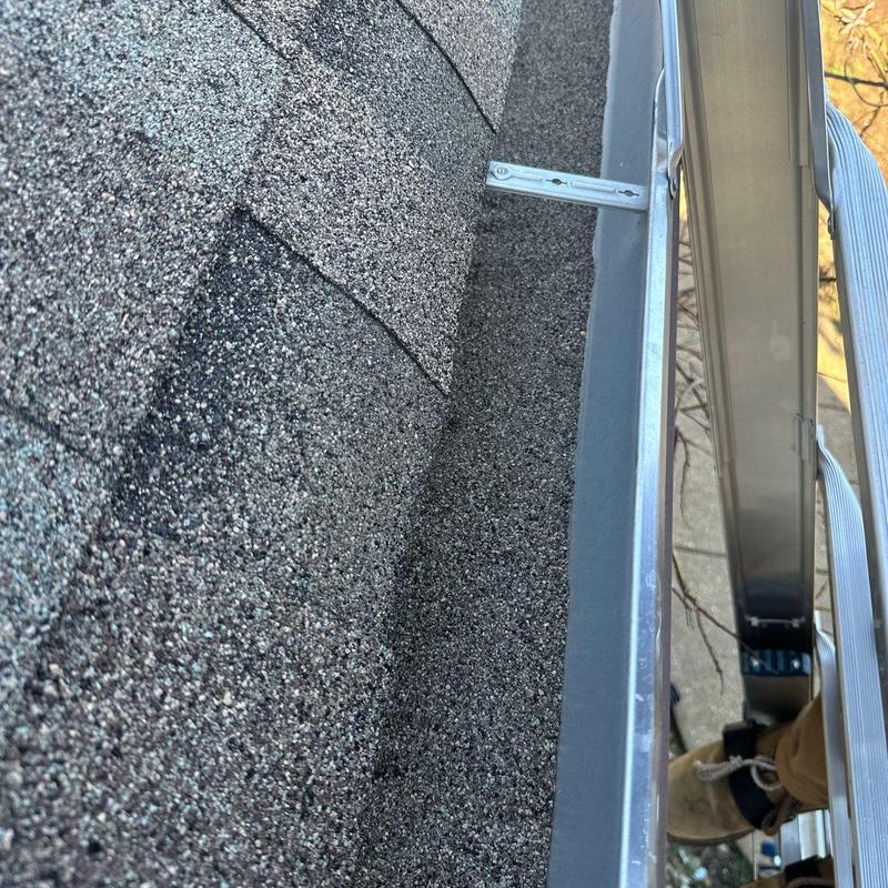 Asphalt shingles with hail damage near metal gutter